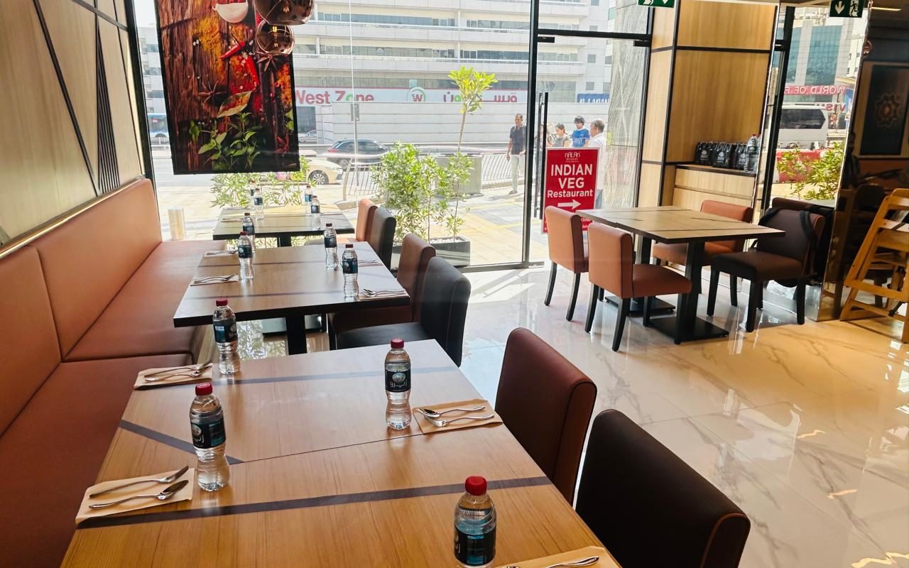 Restaurant with a long orange leather banquette along the window and timber dining tables