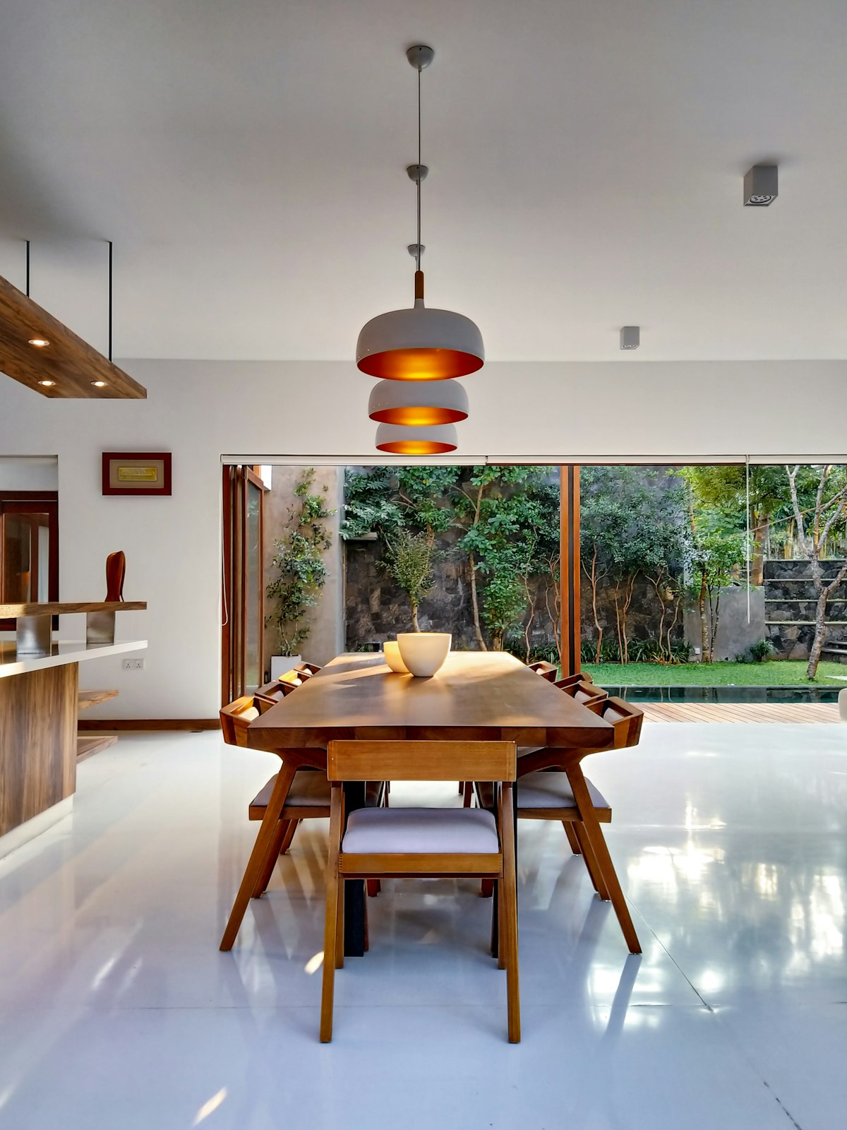 Solid wood dining table with designer pendant lighting in open-plan interior
